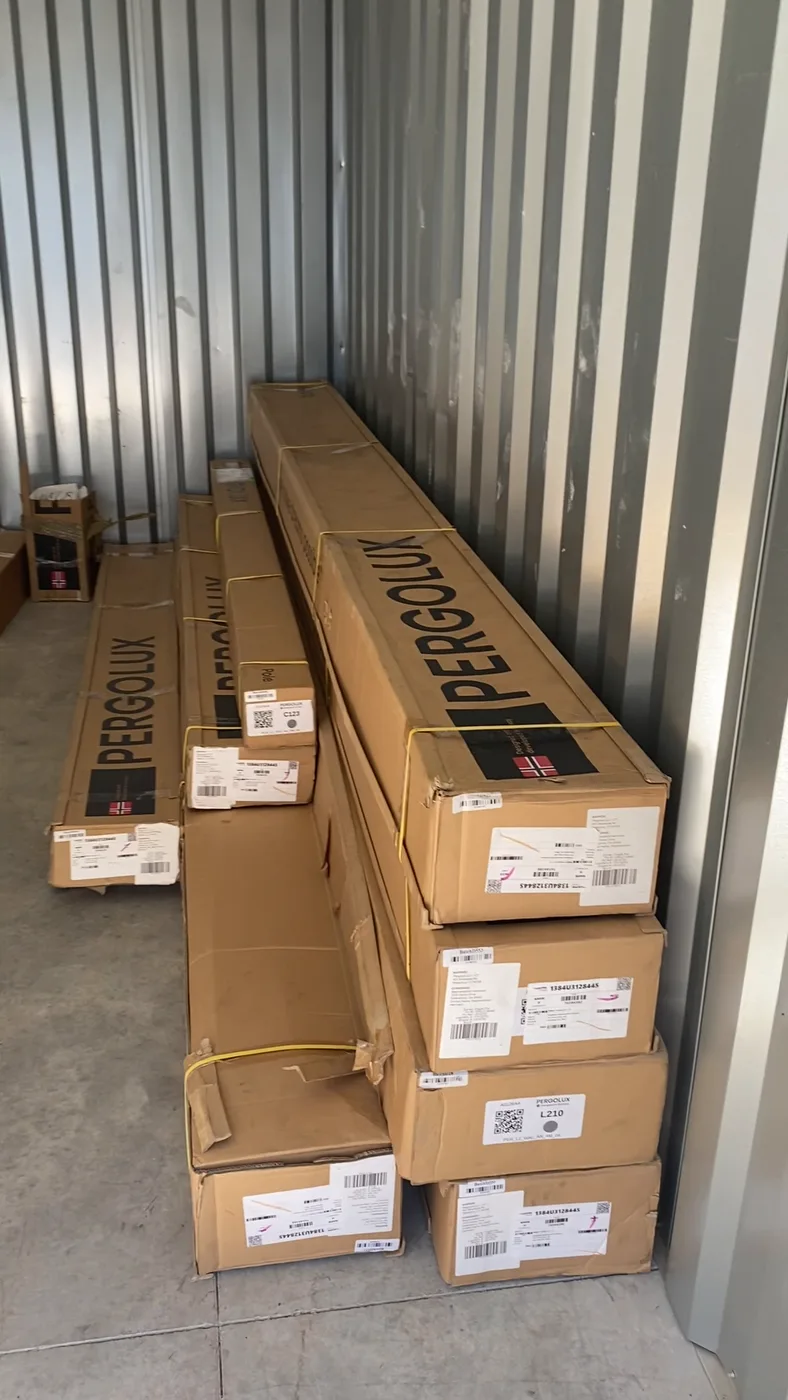Boxed pergola materials stacked neatly in a storage unit by GoldStrap Moving