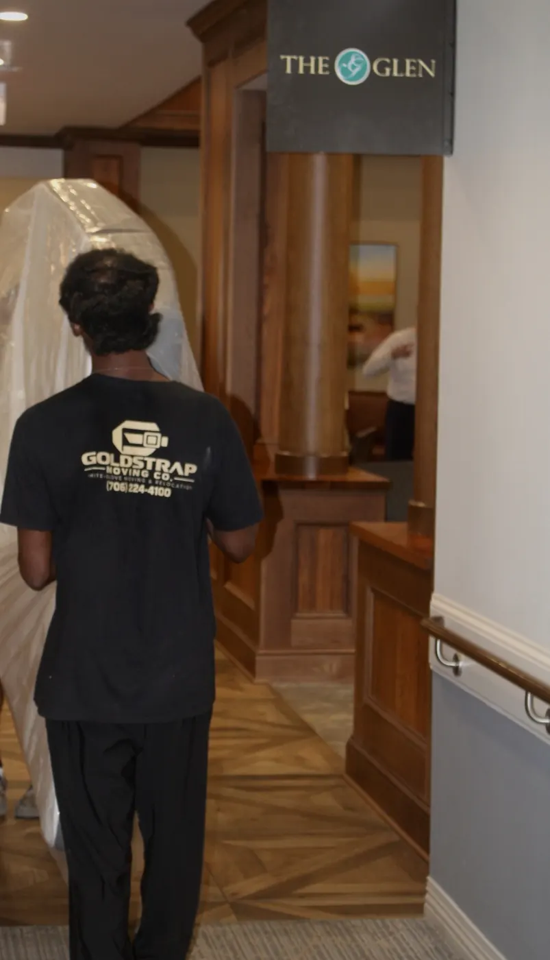 GoldStrap Moving crew carrying a bagged mattress through a hallway in Greensboro, GA